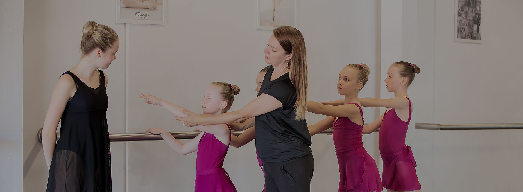 Teacher assisting ballet students at the barre